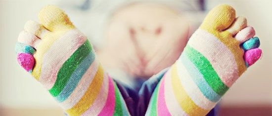 Colorful striped socks on feet, emphasizing foot comfort and care, relevant to pregnancy foot health and pampering tips.
