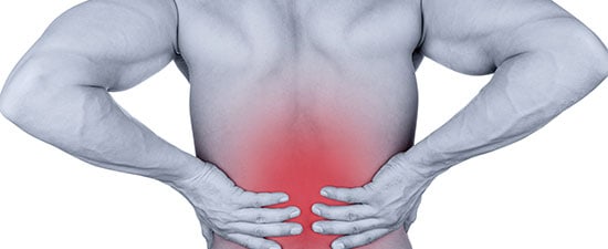 Man grasping lower back, indicating pain, relevant to discussions on lower back pain causes and foot health.