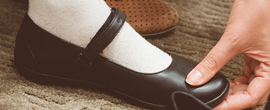 Child's foot being fitted for a black Mary Jane shoe, emphasizing proper shoe fit and comfort for children's foot health.