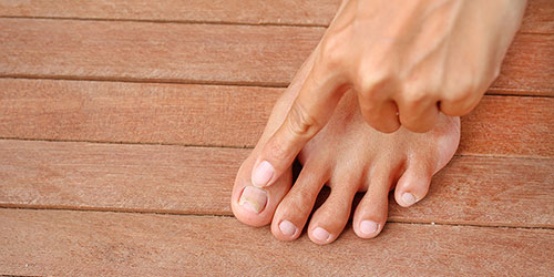 Person examining an ingrown toenail on their foot, highlighting the importance of medical attention for toenail conditions.