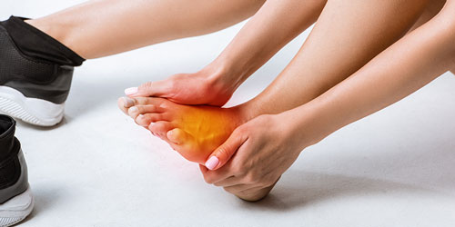 Person holding their foot in pain, highlighting common foot pain issues related to foot and ankle health.