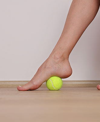 Close up of foot rolling tennis ball