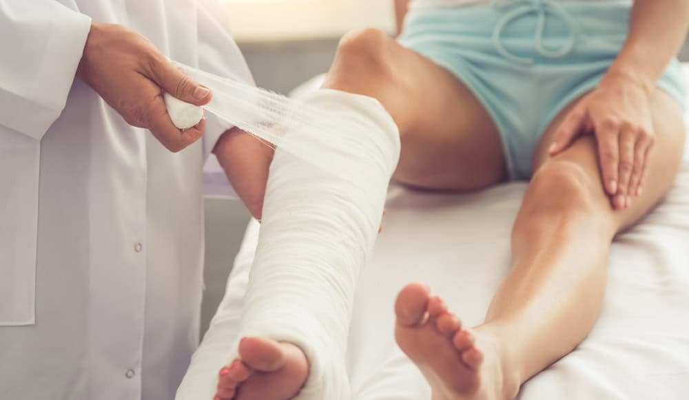 Doctor bandaging patient's ankle