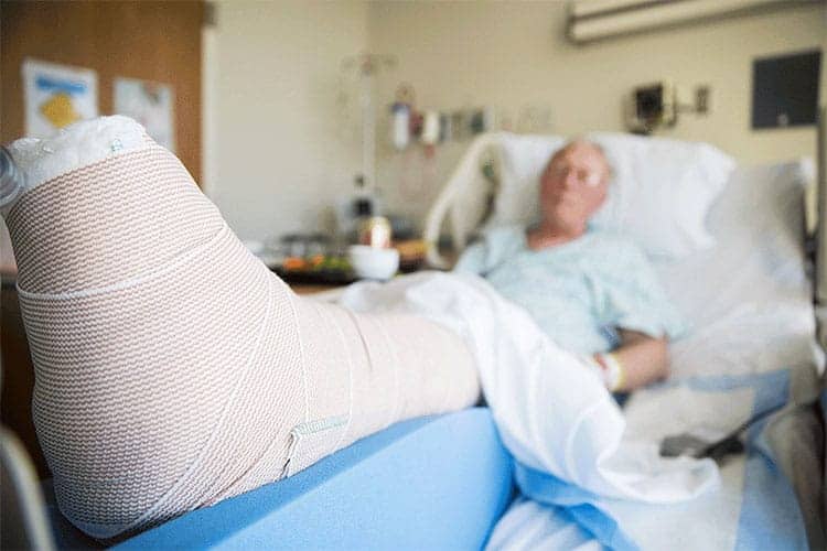 Patient in hospital bed with a bandaged foot, indicating post-surgical care related to potential surgical site infections.