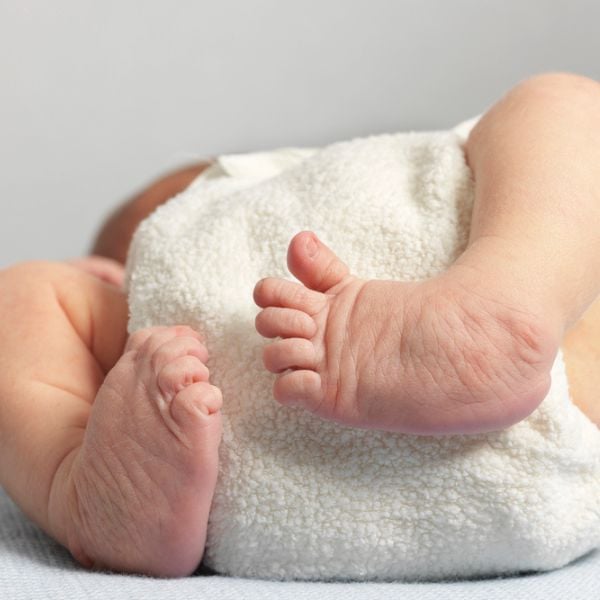 Close-up of a newborn baby's feet resting on a soft white blanket, highlighting tiny toes and delicate skin.
