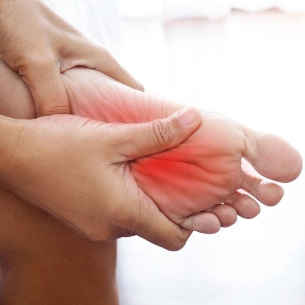 Close-up of a person's foot with redness and discomfort, indicating foot pain or inflammation.
