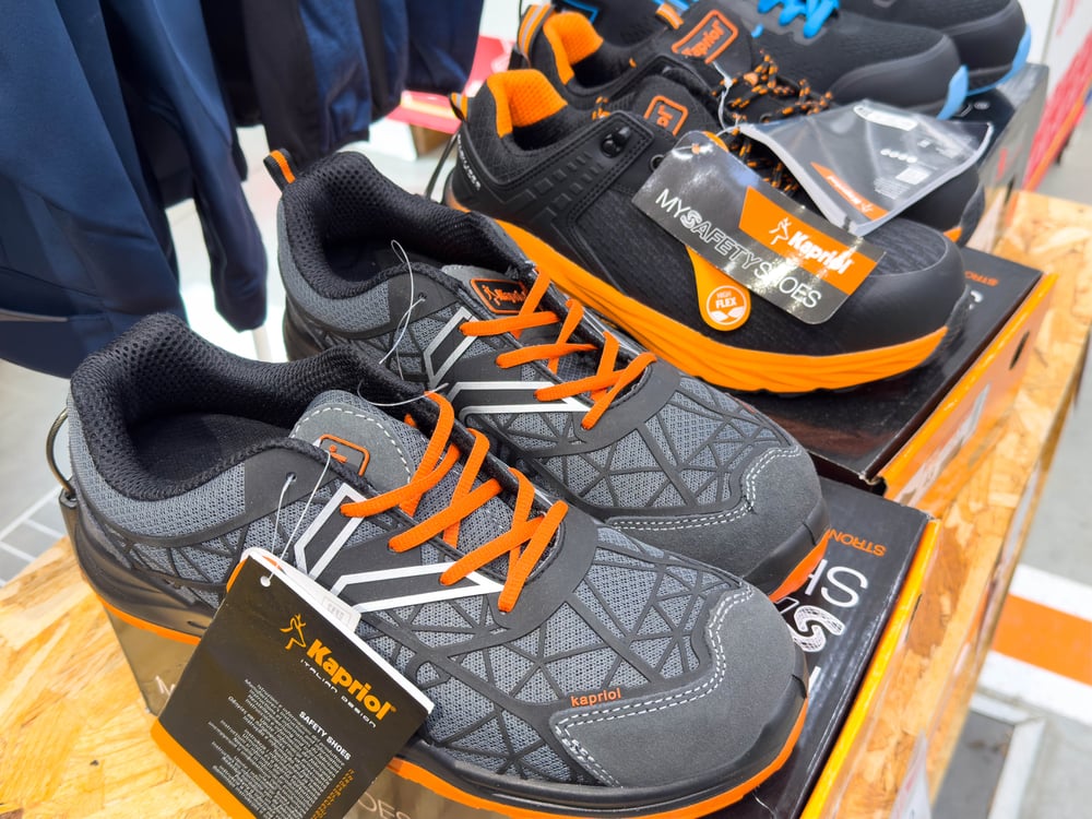 Kapskior athletic shoes displayed on a wooden table with tags, featuring black and orange design suitable for foot health and sports.